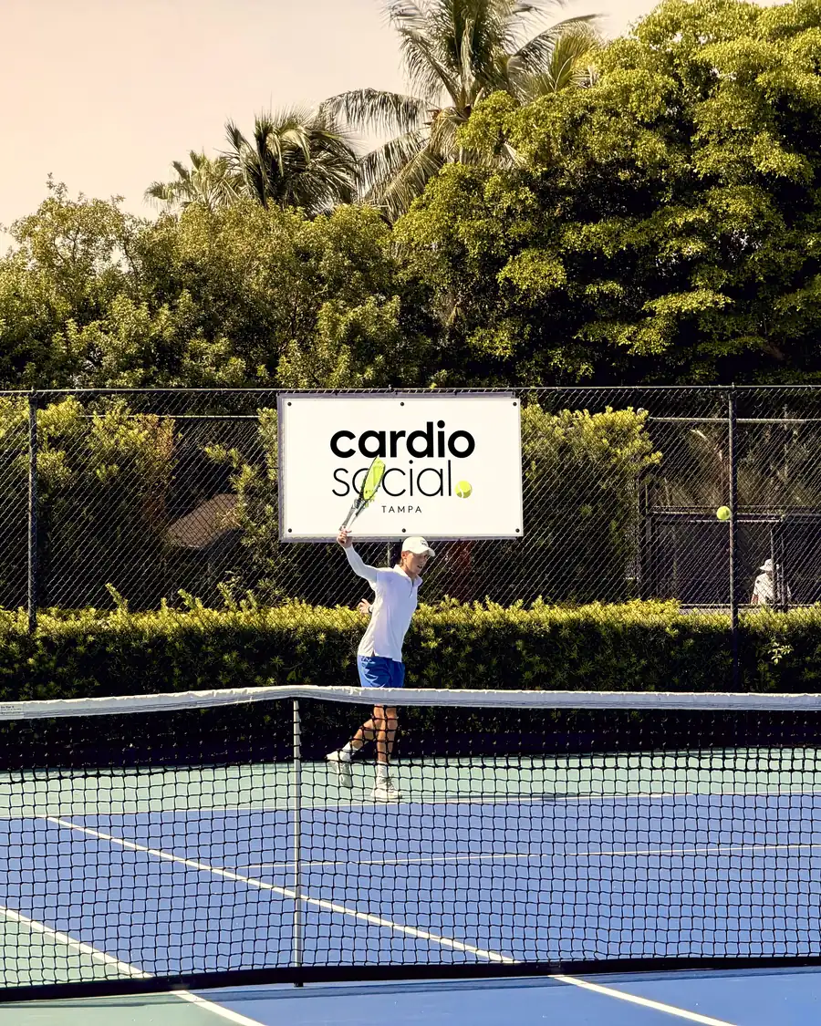 Coach hitting an overhead beneath the Cardio Social banner