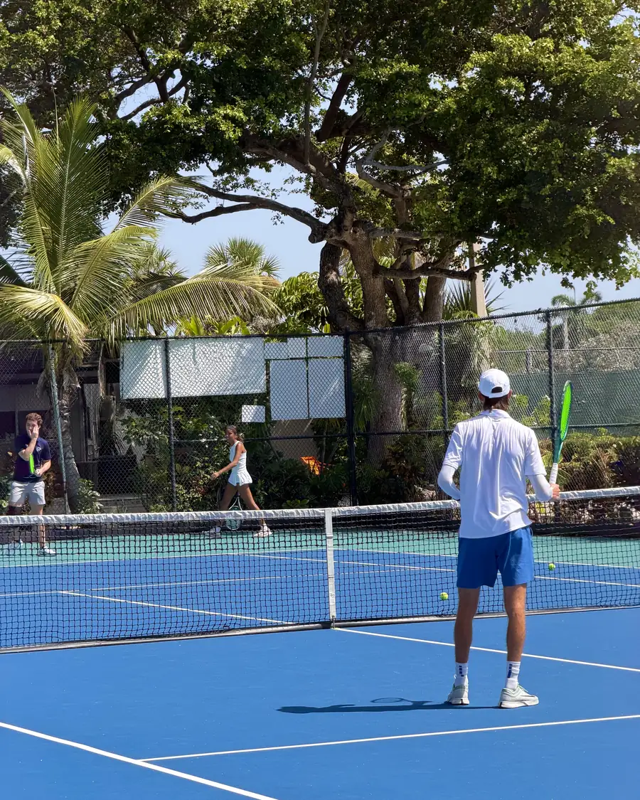 A cardio tennis group spread across the court mid-session