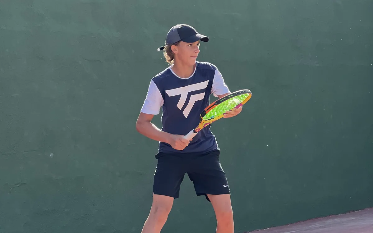 Junior tennis player in ready position on a clay court