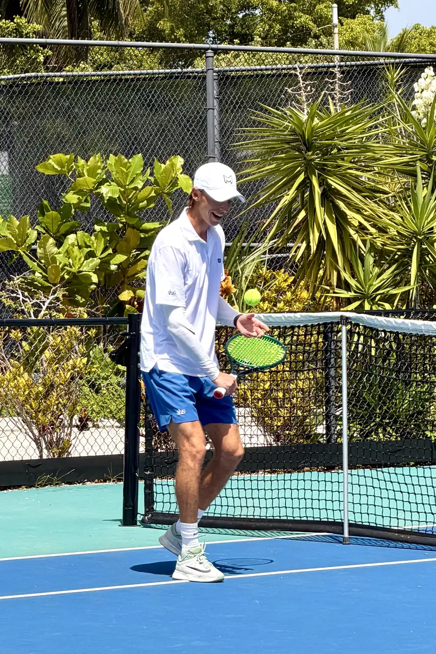 Coach Tom at the net with a ball in the air, mid-session